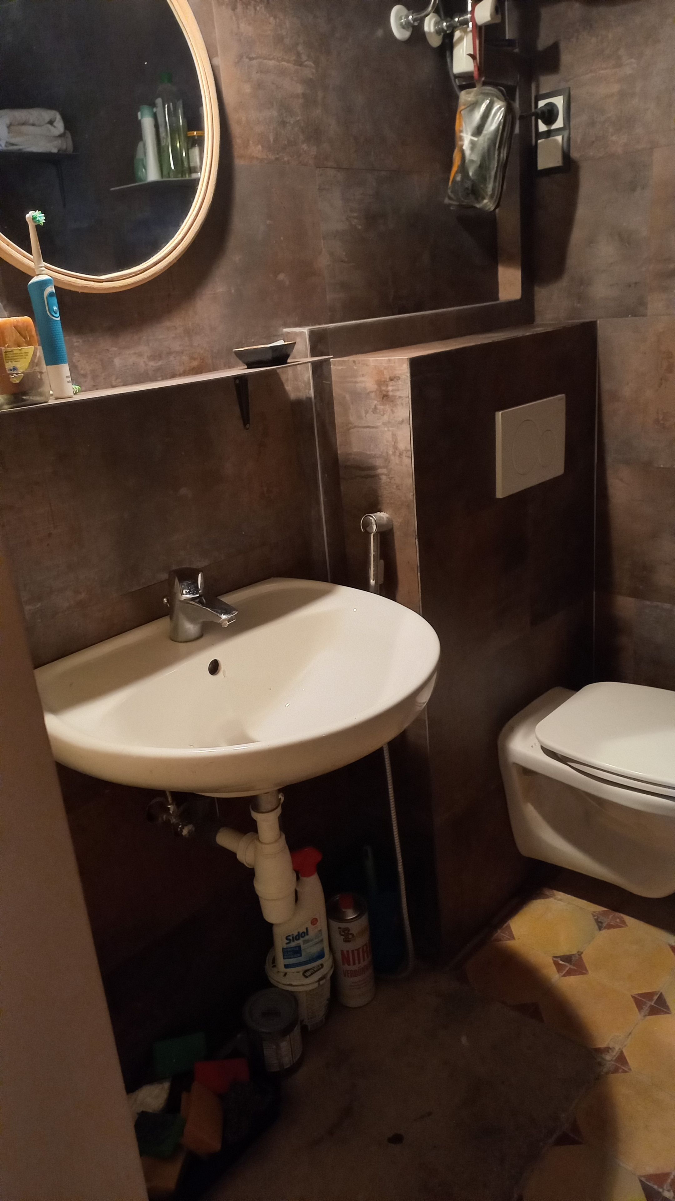 A bathroom with a white sink, a toilet, a mirror, and a towel rack.