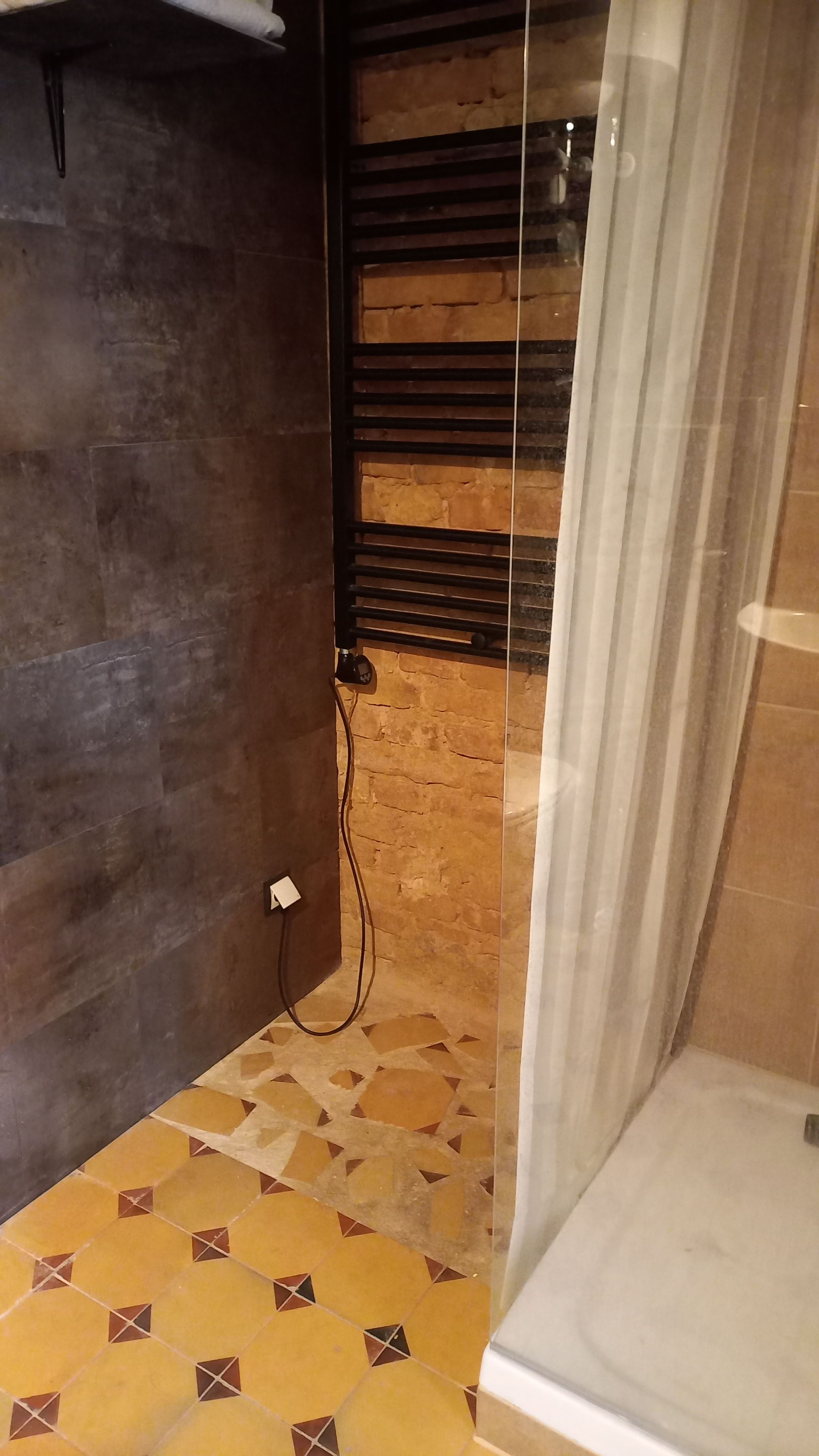 Ein Badezimmer mit gefliestem Boden, einer Duschkabine mit Glastür und einem Handtuchhalter.