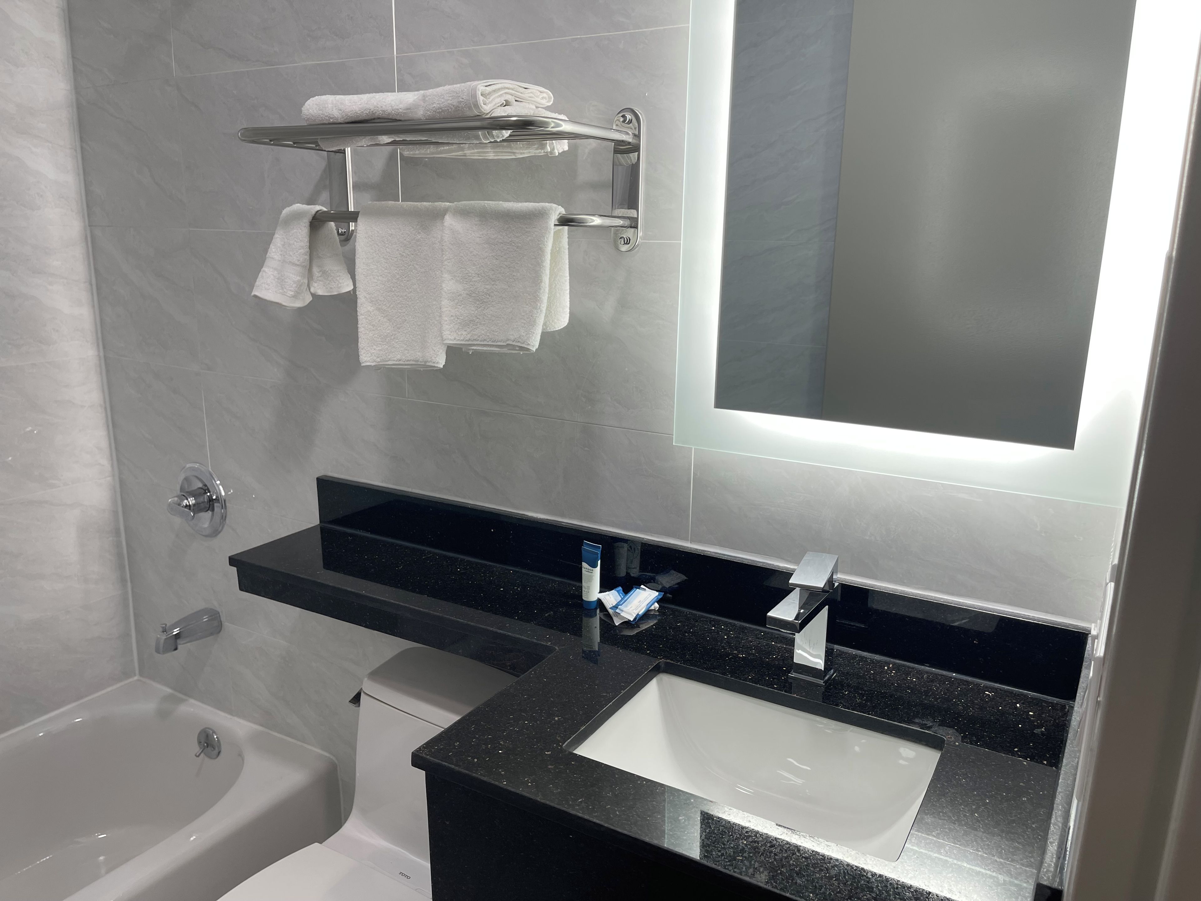 A modern bathroom with a black countertop sink, a mirror, and a towel rack with folded towels.