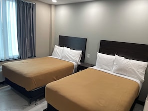 Two single beds with headboards, a window with curtains, and a light switch on the wall. - Fortune Hotel Bronx  (Bronx)