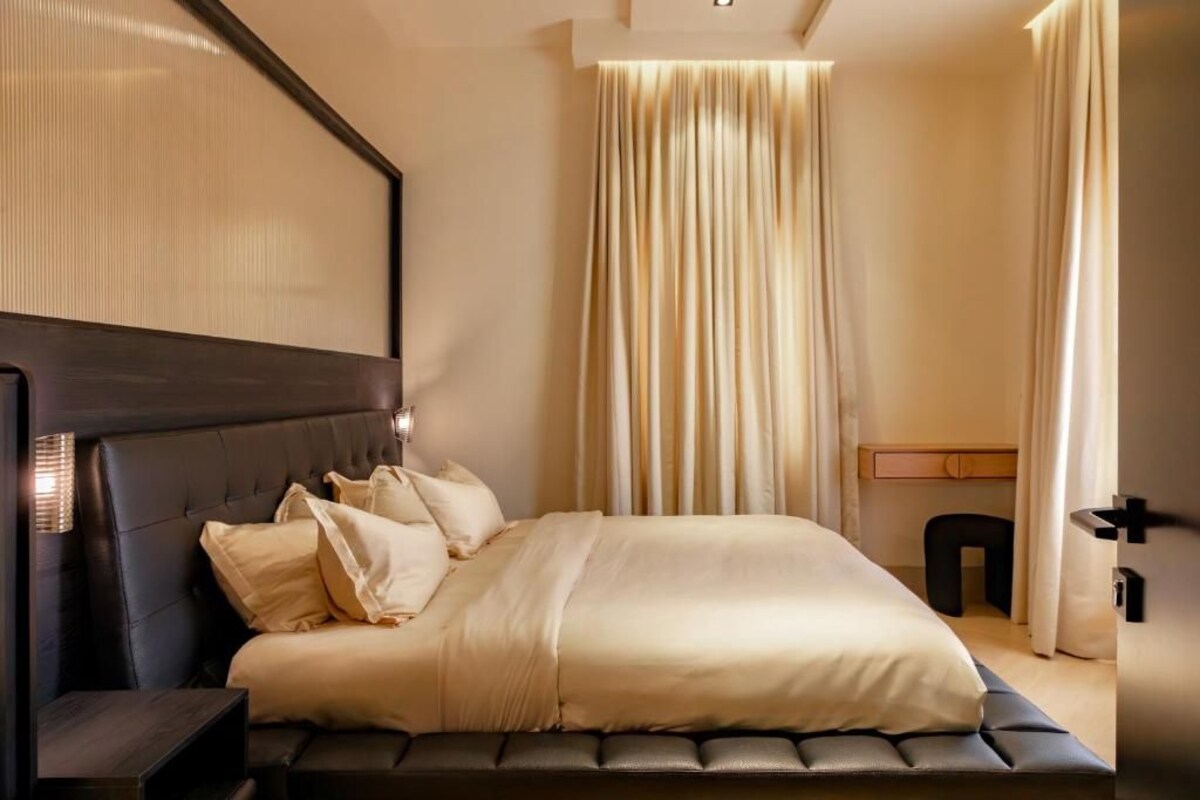 Un dormitorio moderno con una cama grande, cabecero, mesita de noche y lámpara de pared.