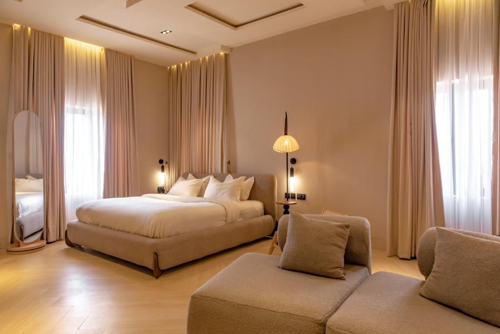 Habitació d'hotel amb un llit gran, un sofà, un mirall i una làmpada.