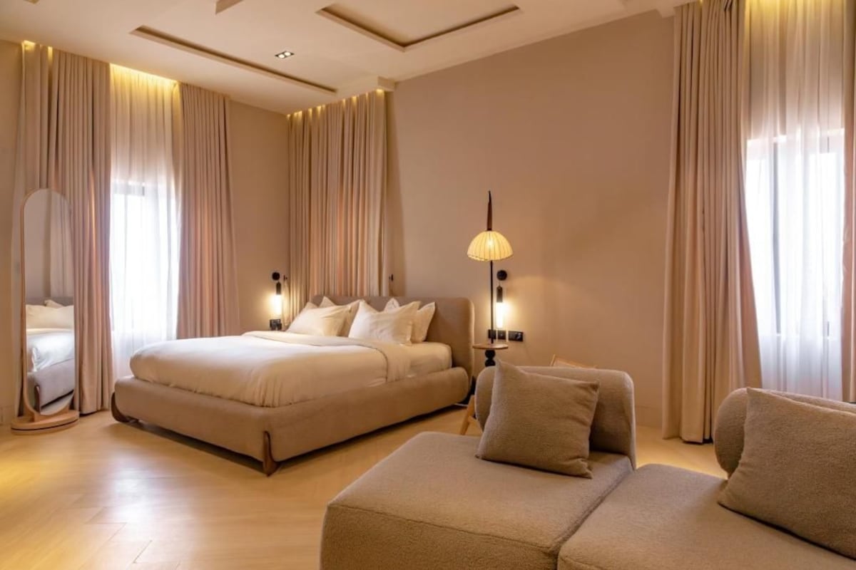 Una habitación de hotel con una cama grande, un sofá, un espejo y una lámpara.