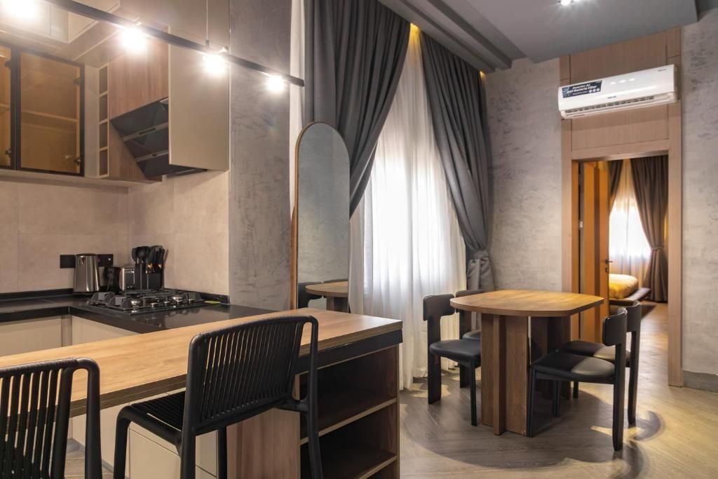 Una cuina moderna amb una illa central, zona de menjador amb taula rodona i cadires, i aire condicionat integrat.