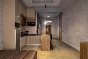 Una cocina moderna con electrodomésticos integrados, un comedor con mesa de madera y un pasillo que conduce a otra habitación.