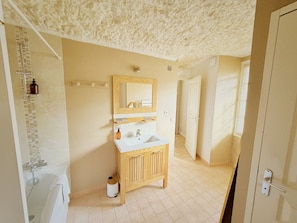 A bathroom with a wooden vanity, a mirror, a sink, and a shower area. - New Listing (Vouvray)