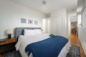 Ein Schlafzimmer mit Bett, Nachttisch, Lampe und Wanddekoration.