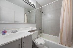 Ein Badezimmer mit Waschbecken, Spiegel, Toilette und Badewanne.
