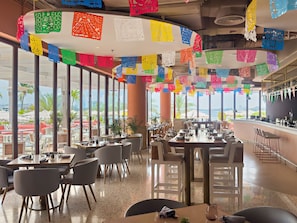 A restaurant with tables and chairs, large windows, and colorful paper decorations. - Luxury 3BD Apartment in Palm Jumeirah | Marina Views & Stunning Sunsets (Dubai)