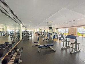 A gym with various exercise equipment, a bench, and a mirror on the wall. - Luxury 3BD Apartment in Palm Jumeirah | Marina Views & Stunning Sunsets (Dubai)