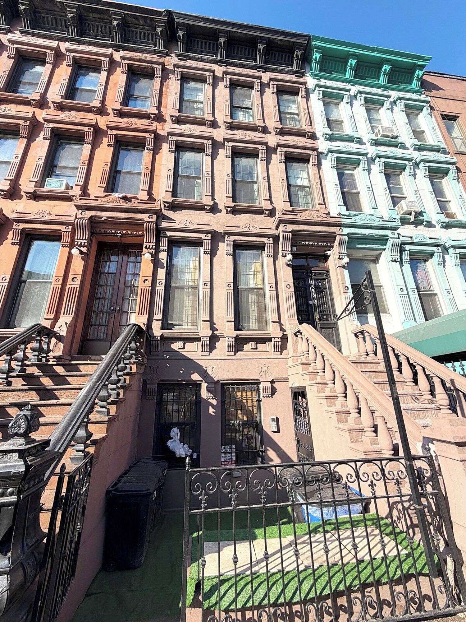 A row of brownstone buildings with a central staircase leading to the entrance.