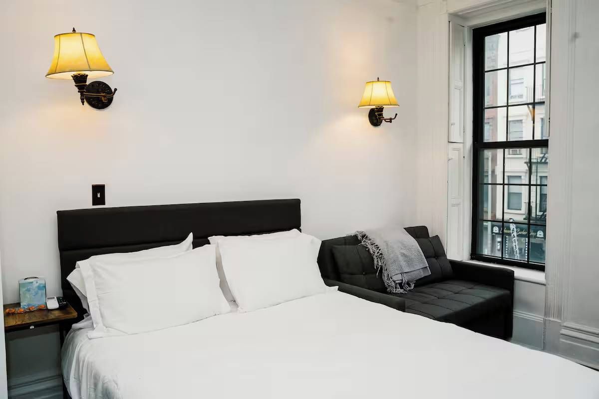 A hotel room with a bed, bedside tables, lamps, and a window with a view.