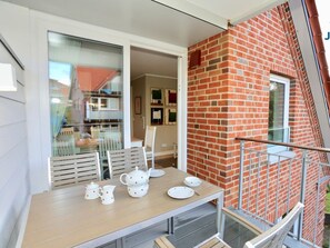 A dining area with a table set for four, a brick wall, and a glass door leading to a balcony. - 213 - Apartment 13 "red Crab" (Juist)
