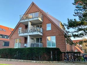 A two-story residential building with a balcony on the upper floor, a stone wall in front, and bicycles parked outside. - 213 - Apartment 13 "red Crab" (Juist)
