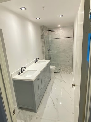 Un bagno moderno con lavabo doppio, box doccia in vetro e pavimento in marmo.