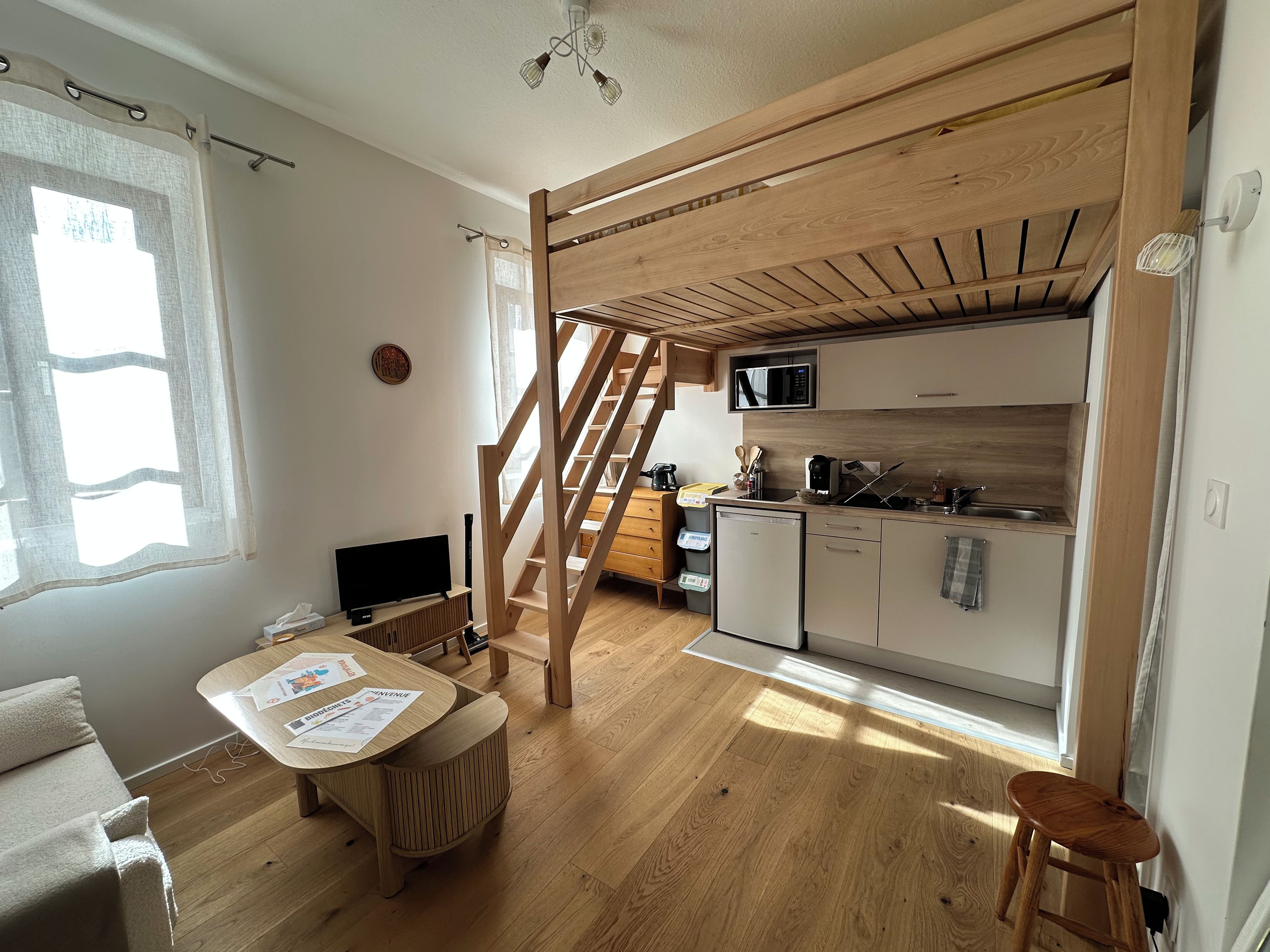 Cocina compacta con microondas, pileta y armarios de madera.