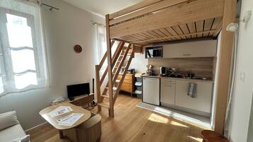 Cocina compacta con microondas, pileta y armarios de madera.