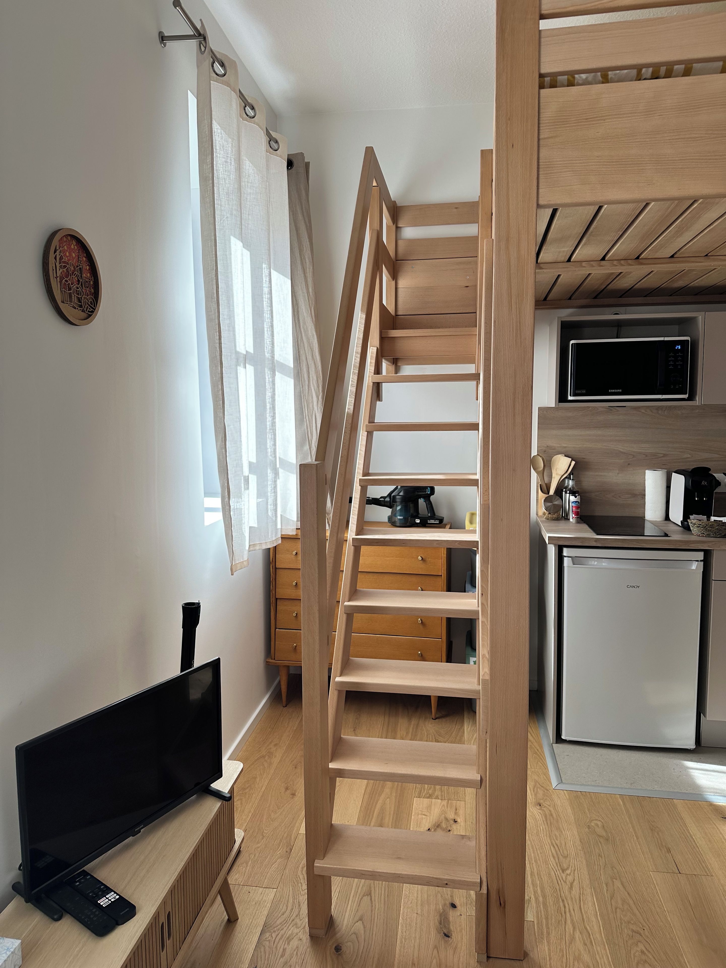 A modern kitchen with a built-in microwave, a coffee machine, and a refrigerator.
