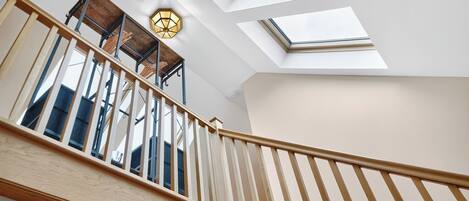 A staircase with wooden railings and a skylight above.