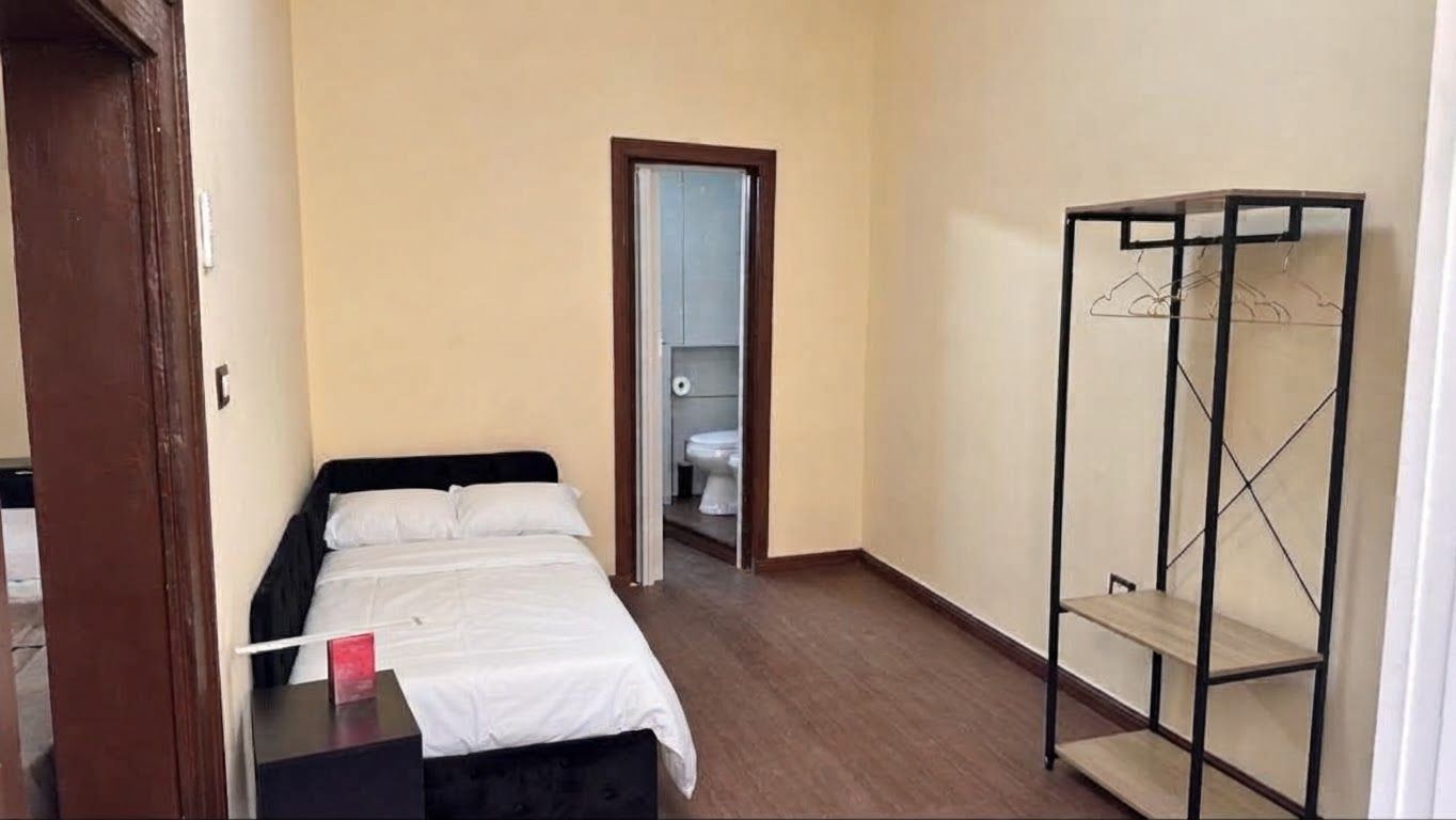 A bedroom with a bed, a wardrobe, and a door leading to a bathroom.