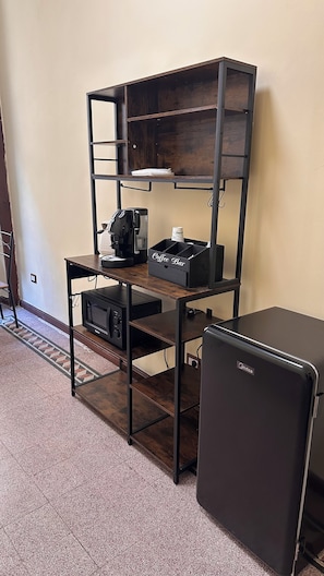 A compact kitchenette with a microwave, coffee maker, and a refrigerator. - New Listing (Napoli)