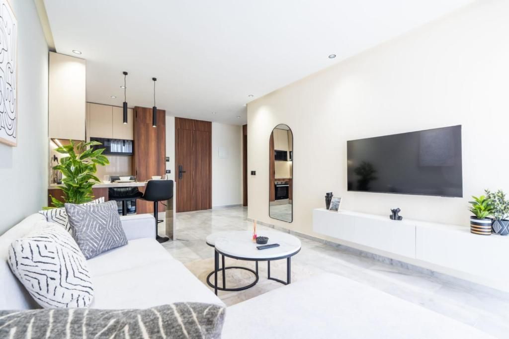 Een moderne woonkamer met een bank, salontafel en een aan de muur bevestigde televisie.