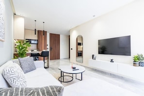 Een moderne woonkamer met een bank, salontafel en een aan de muur bevestigde televisie.