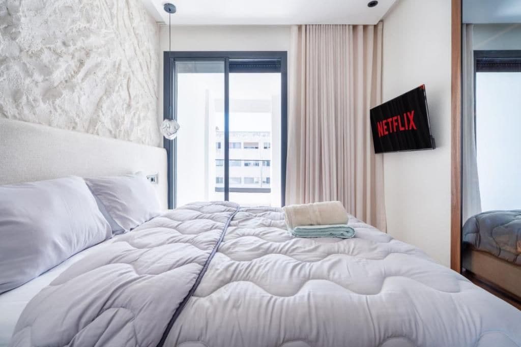 Een hotelkamer met een bed, een televisie aan de muur en uitzicht op de skyline.