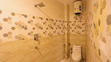 Un baño con ducha, inodoro y un pared con azulejos de diseño hexagonal.