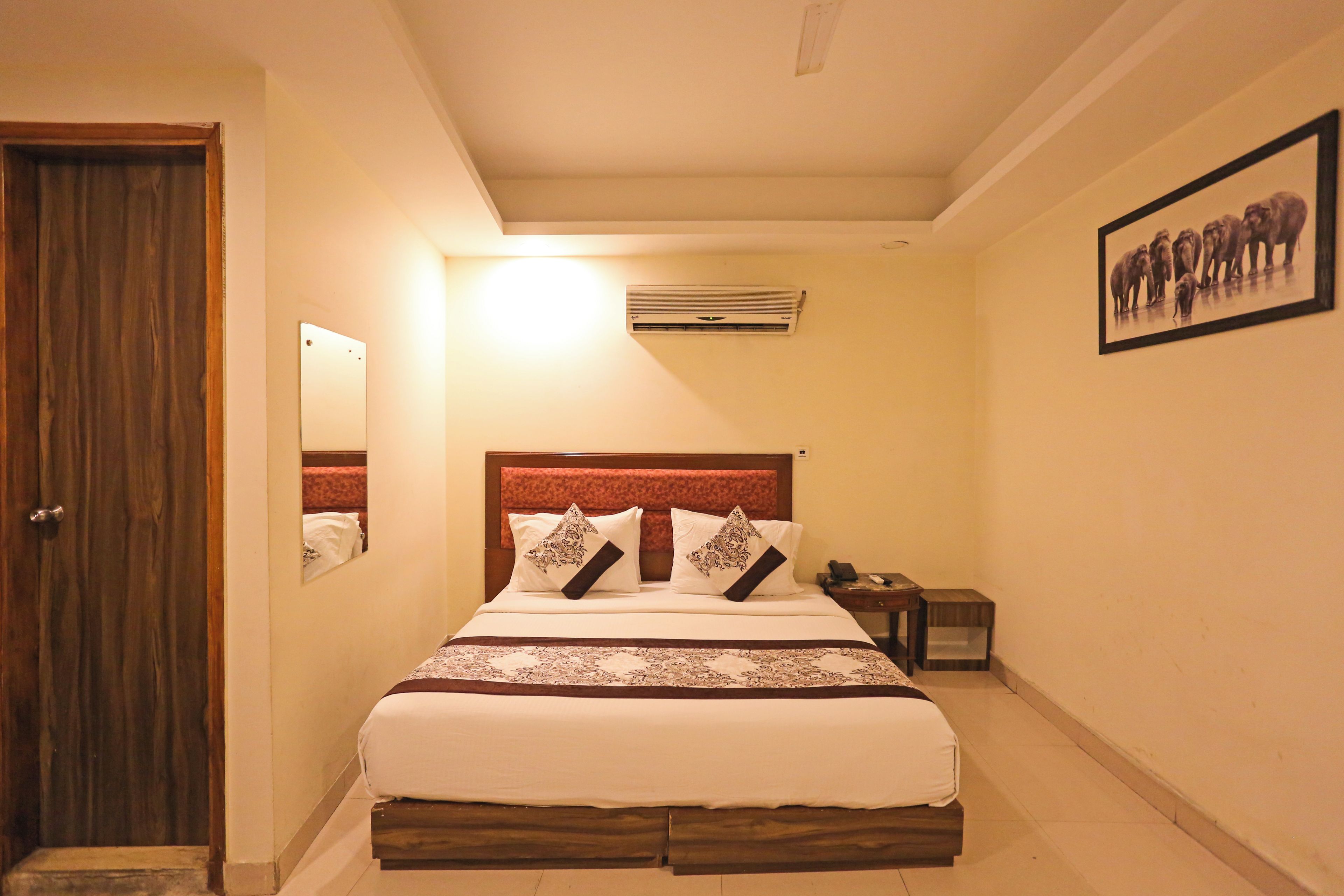 Una habitación de hotel con cama, mesita de noche y un cuadro enmarcado en la pared.