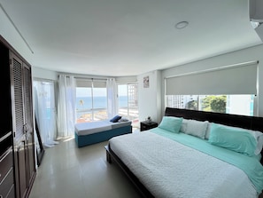 Una camera da letto con un letto grande, un comodino, una finestra vista mare e un balcone.