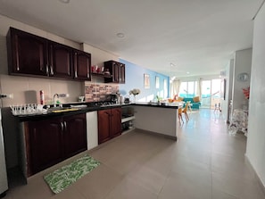 Una cucina moderna con pensili scuri in legno, un piano di lavoro nero e un tappetino verde all'ingresso.