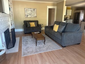 Ein Wohnzimmer mit zwei grauen Sofas, einem Couchtisch und einem Kamin.