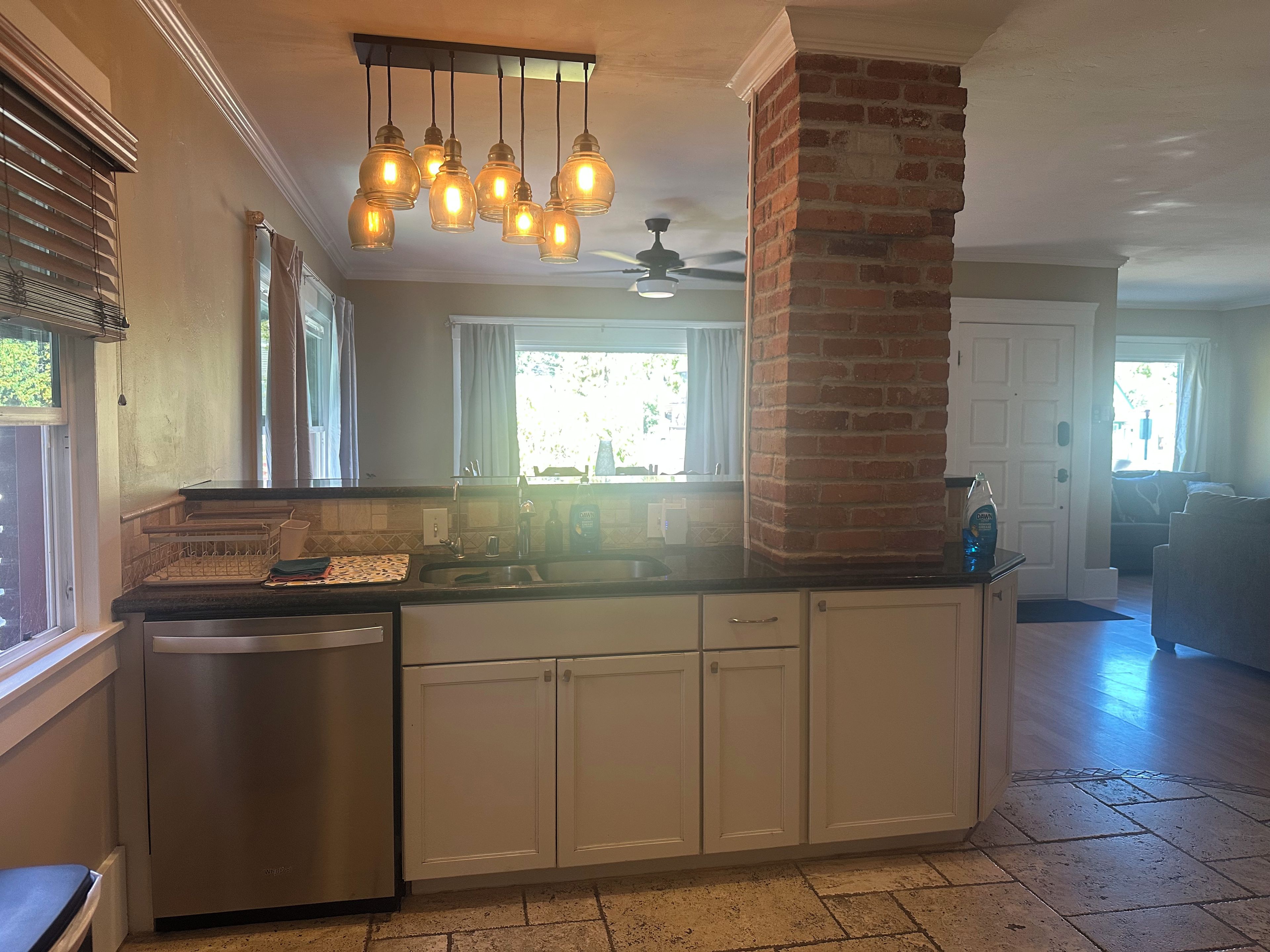 A kitchen with a central island, white cabinetry, a brick accent wall, and pendant lighting.