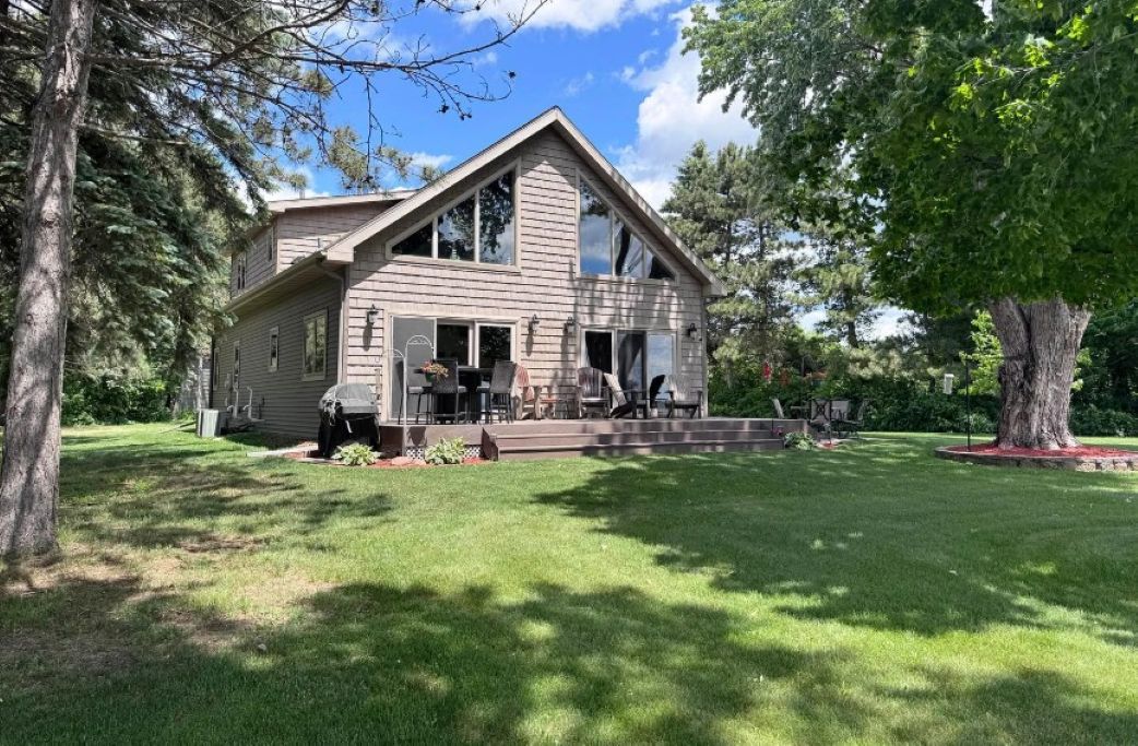 A two-story house with a front porch, a covered outdoor seating area, and a well-maintained lawn.
