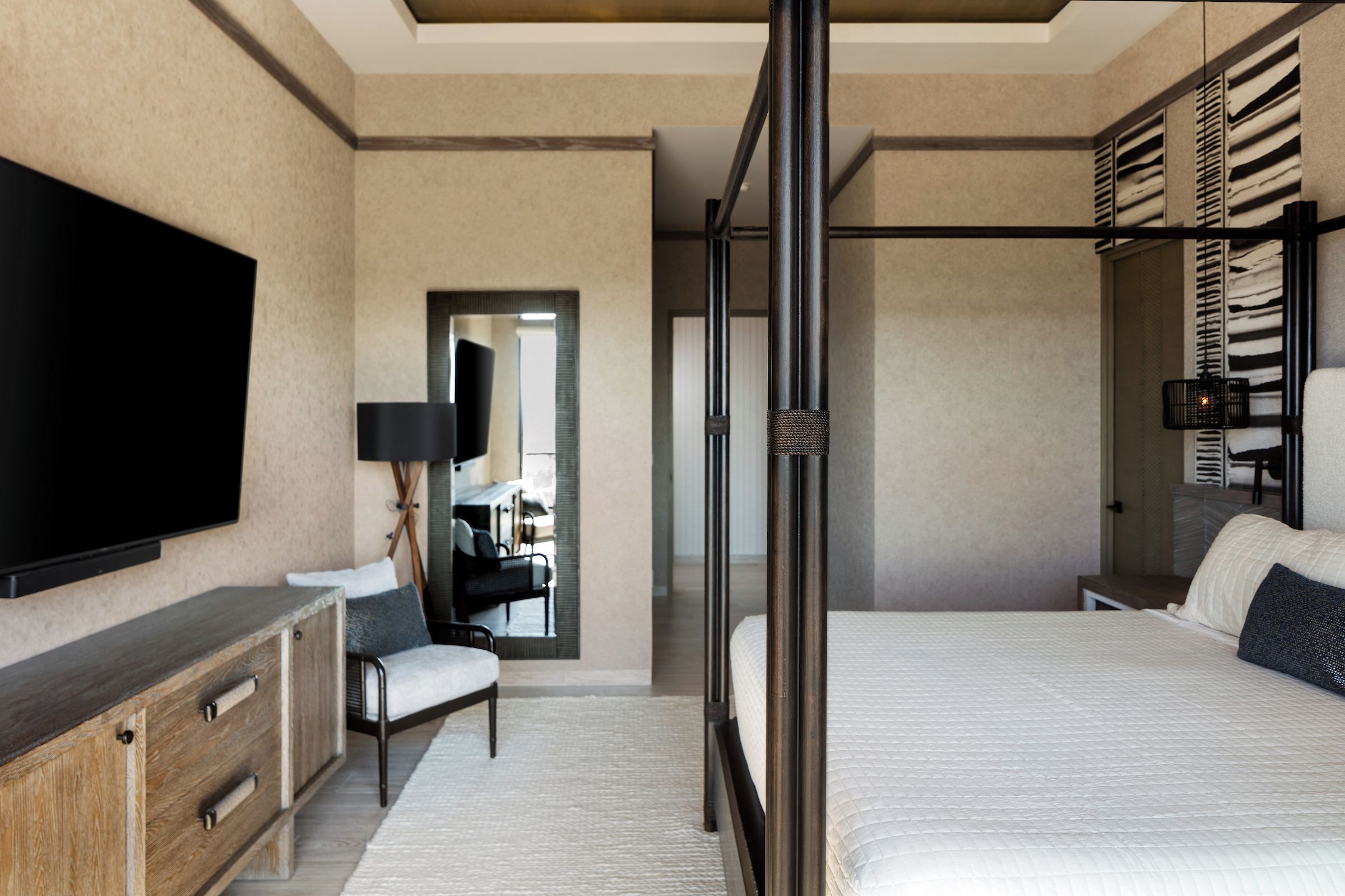 A modern bedroom with a large bed, a TV, a desk, and a wardrobe.
