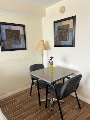 A dining area with a table, chairs, a vase with flowers, and two framed artworks on the wall. - Cozy 1-bedroom condo in pleasant Daytona Beach with AC and gym (Daytona Beach)