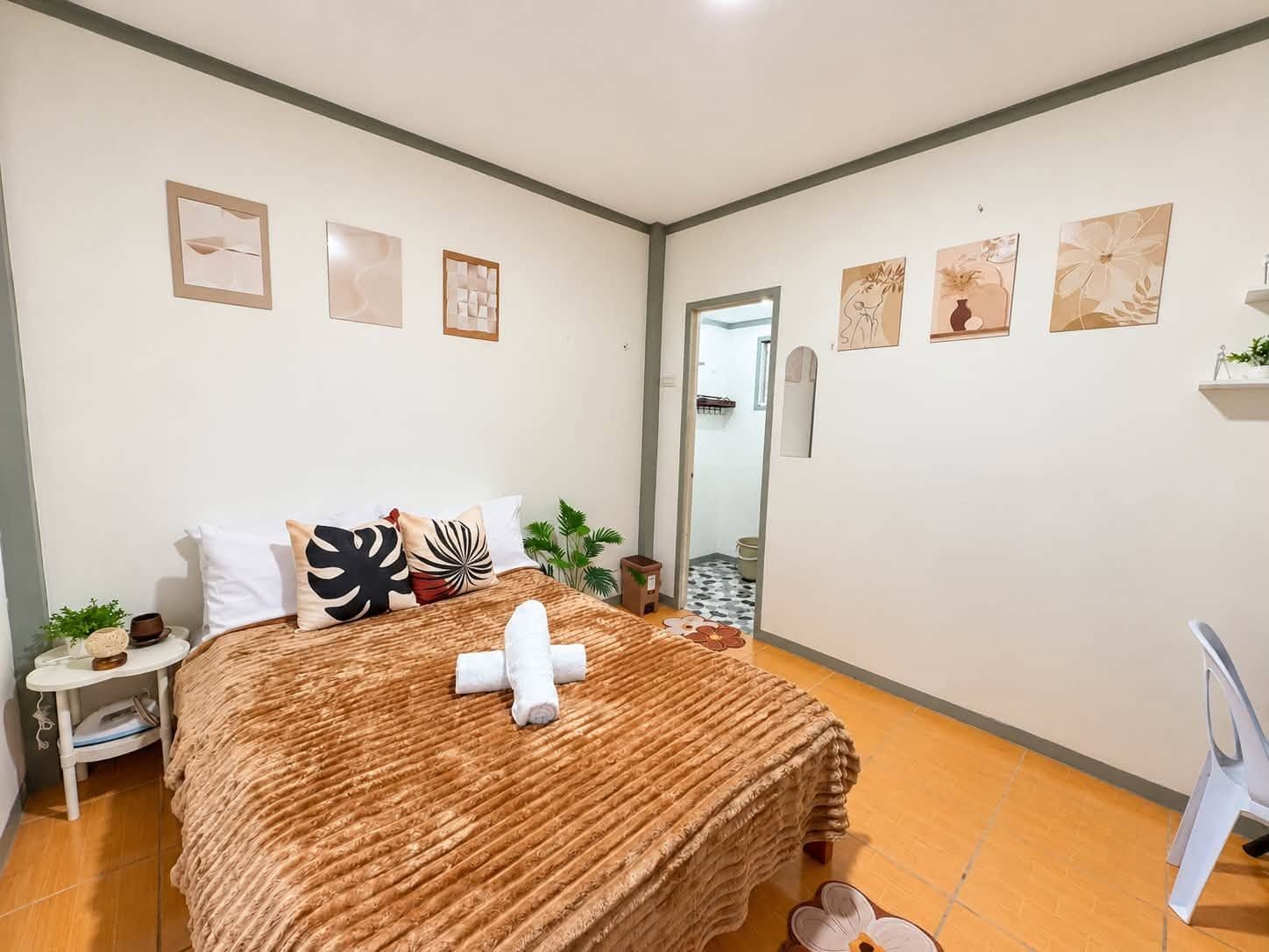 A bedroom with a bed, pillows, a bedside table, a mirror, and artwork on the walls.