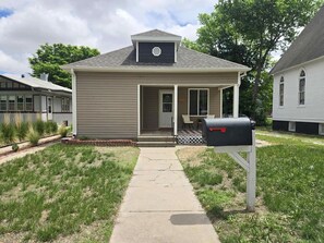 Ein eingeschossiges Haus mit Veranda, Briefkasten und kleinem Garten.