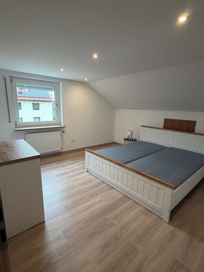 Une chambre avec un lit, une fenêtre, un radiateur et un bureau.