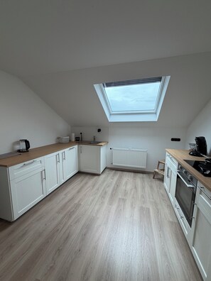 Une cuisine moderne dotée d’une verrière, de meubles blancs et d’un plan de travail en bois.