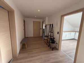 A hallway with wooden flooring, a bench, a black ladder, and a basket with a plant. - New Listing (Lonnerstadt)