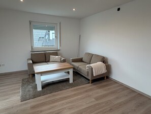 Un salon moderne avec deux canapés, une table basse et une grande fenêtre.