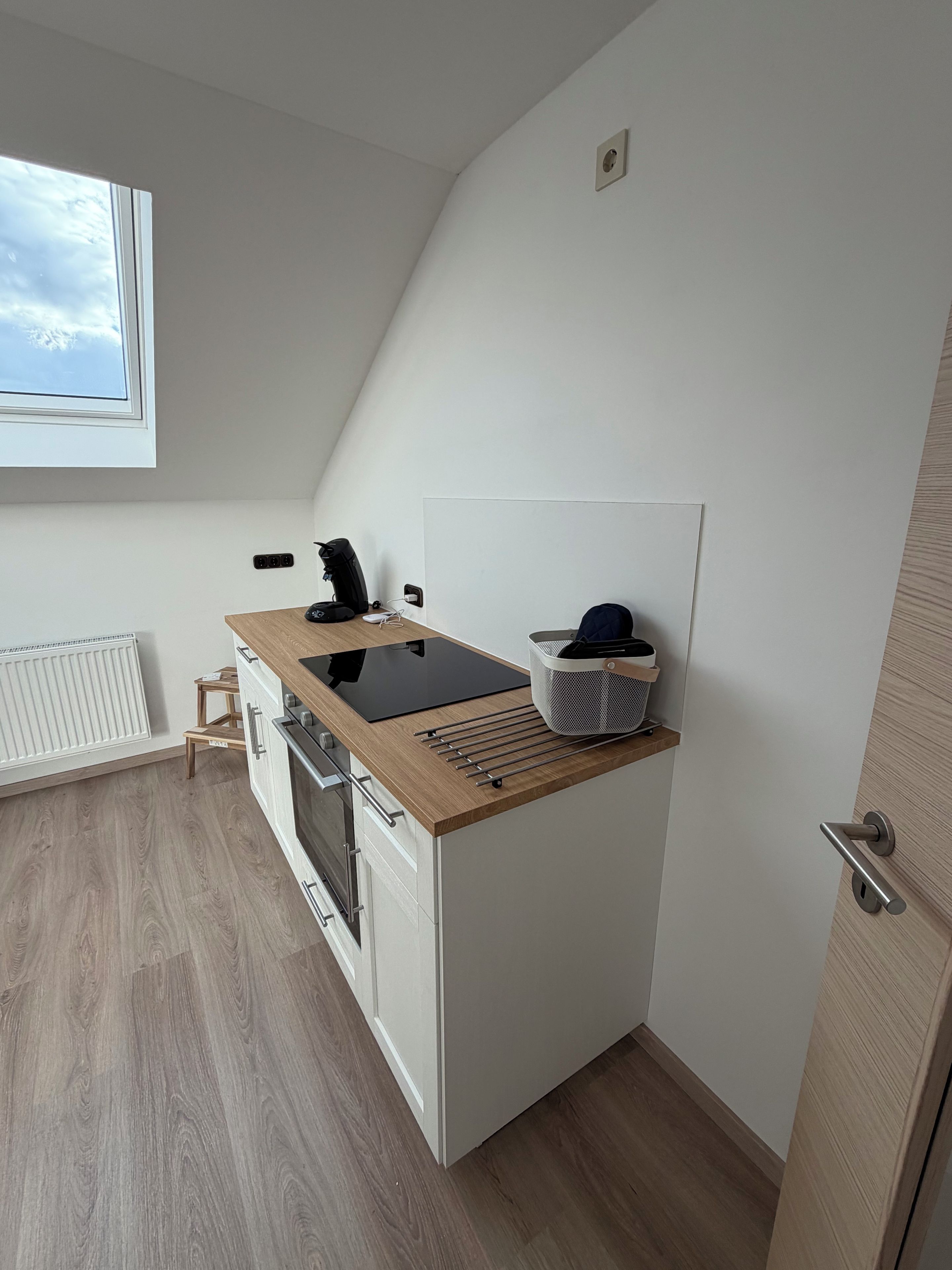A compact kitchen with a built-in stove, a coffee machine, and a small window.
