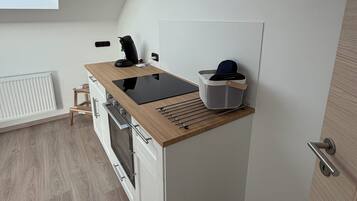 A compact kitchen with a built-in stove, a coffee machine, and a small window.