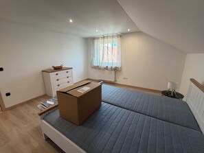 A bedroom with a bed, a dresser, a window with curtains, and a radiator. - New Listing (Lonnerstadt)