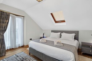 Een slaapkamer met een bed, een nachtkastje, gordijnen en een dakraam.
