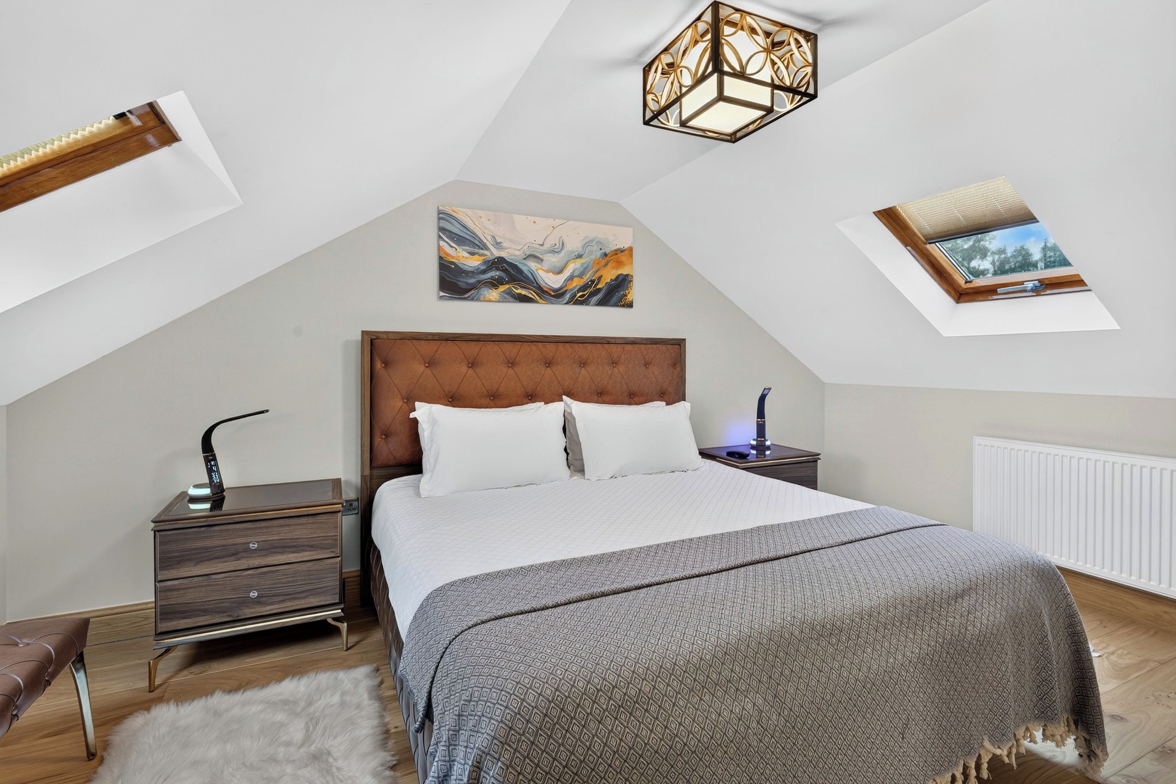 A bedroom with a large bed, a nightstand, a dresser, a radiator, and a ceiling light fixture.