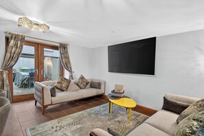Een woonkamer met een bank, een salontafel en een flatscreen televisie aan de muur.