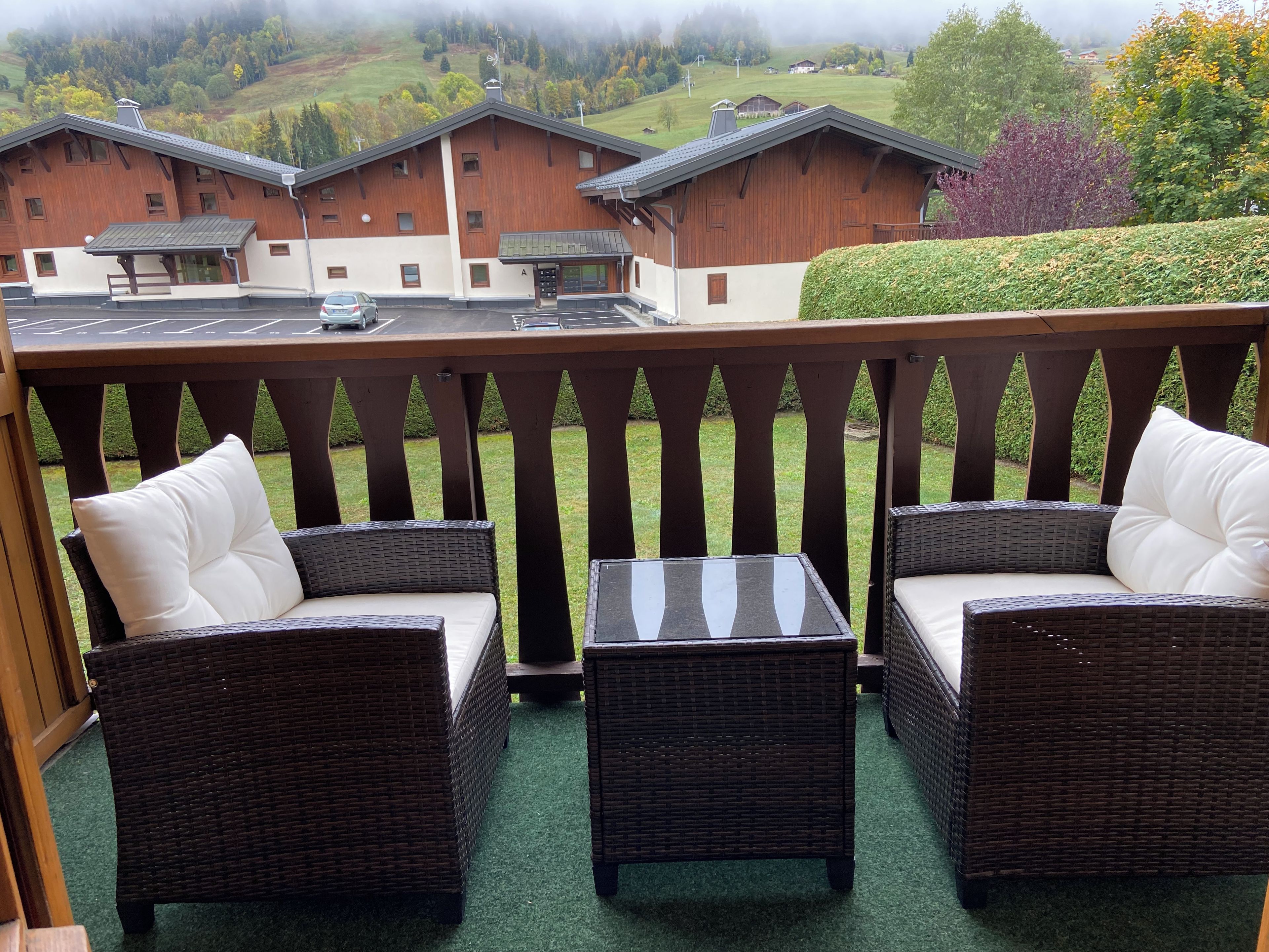 A balcony with wicker furniture and a view of buildings in the background.